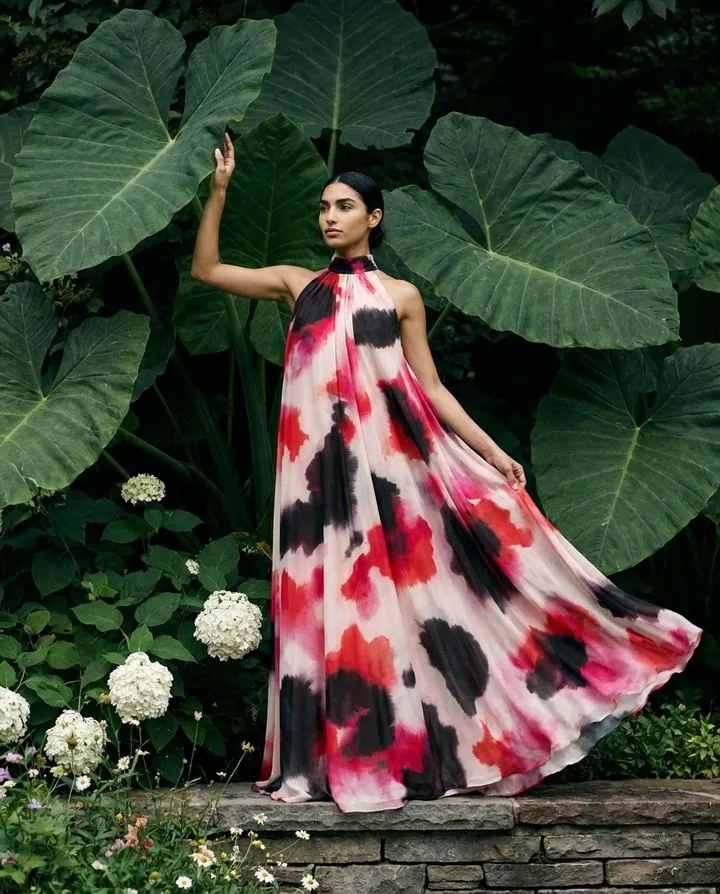 Flowing red and black floral halter gown among giant tropical leaves